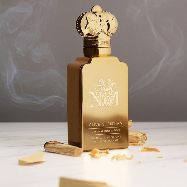 Clive Christian No1 bottle on a dark surface beside gold objects