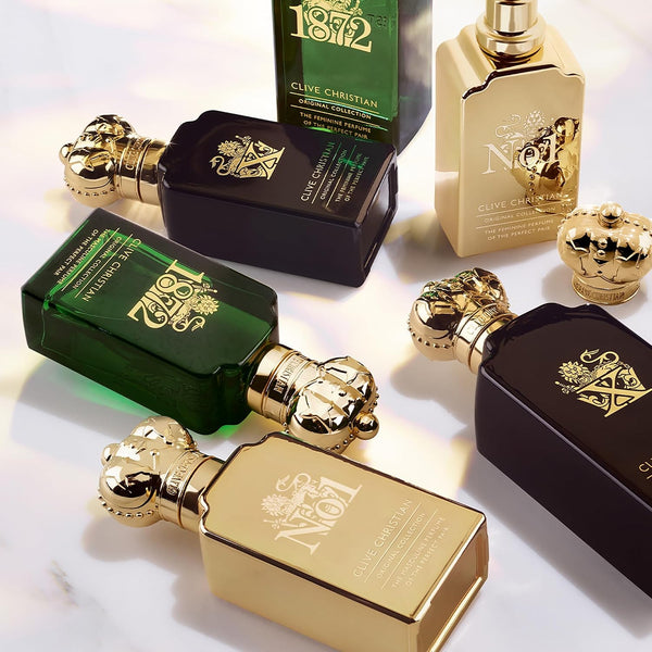 Several Clive Christian Original Collection bottles with crown stoppers lying on a light surface